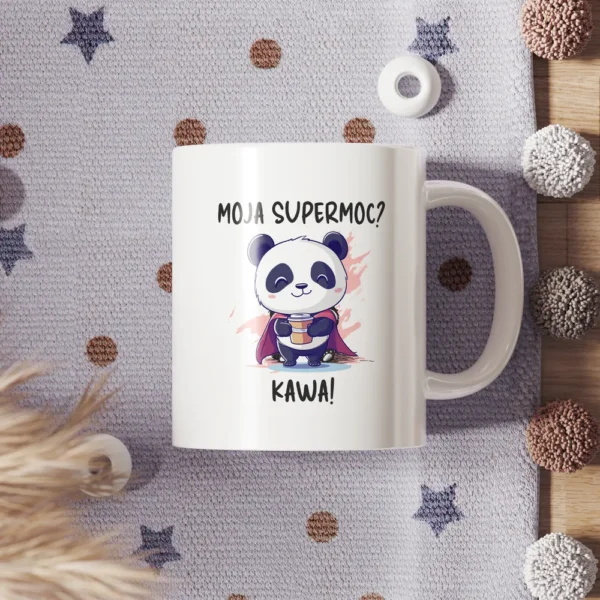 Grafika na kubku przedstawiająca pandę w stroju superbohatera z napisem "Moja supermoc? Kawa!"